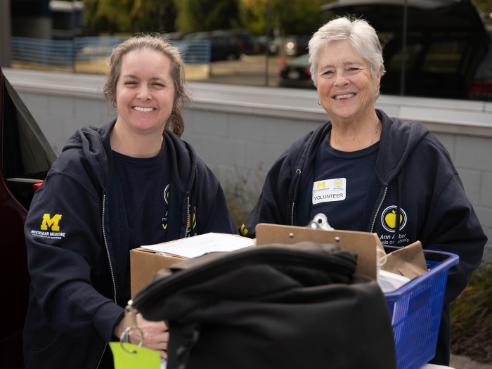 Two Ann Arbor Meals on Wheels volunteers outside with bins