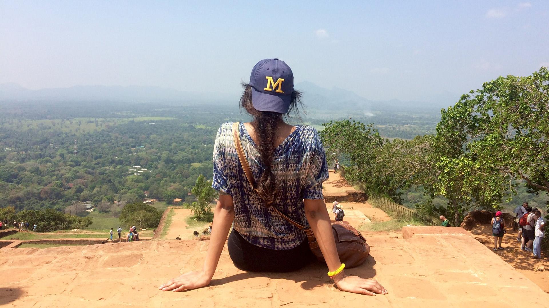 A female student in a Michigan hat looks out at the landscape of Sri Lanka