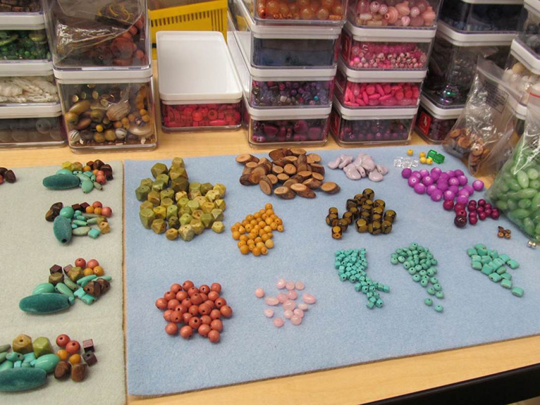 Colorful beads on felt mats with containers of beads behind