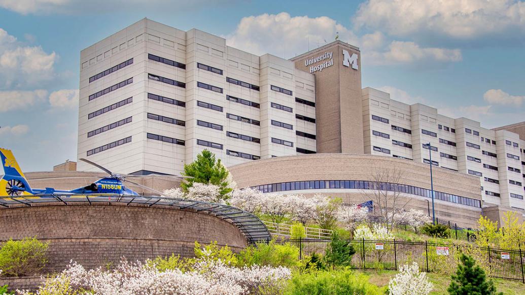 University Hospital at U-M Health in the spring with flowering trees in foreground and Survival Flight helicopter visible
