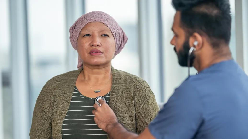 Woman with a headscarf having her heart checked by a man with a stethoscope.