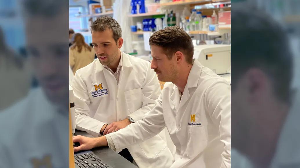 scientists together at computer in white coats