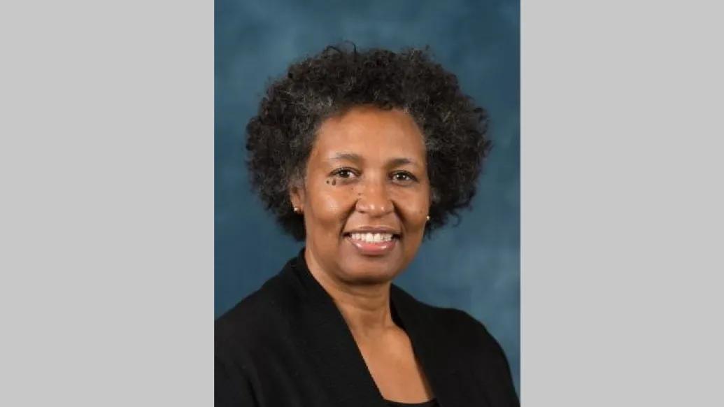Professional portrait of a middle aged Black woman with short curly hair wearing a black blazer