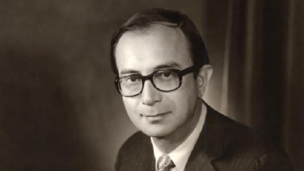 Vintage looking black and white portrait of a middle aged white man wearing a suit and glasses