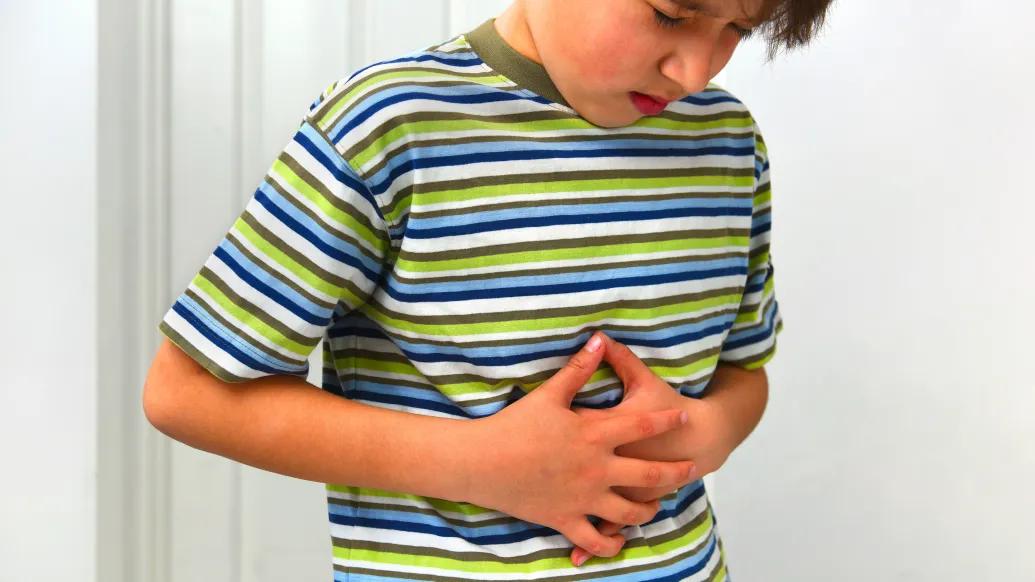 kid holding stomach with stripped shirt green blue white