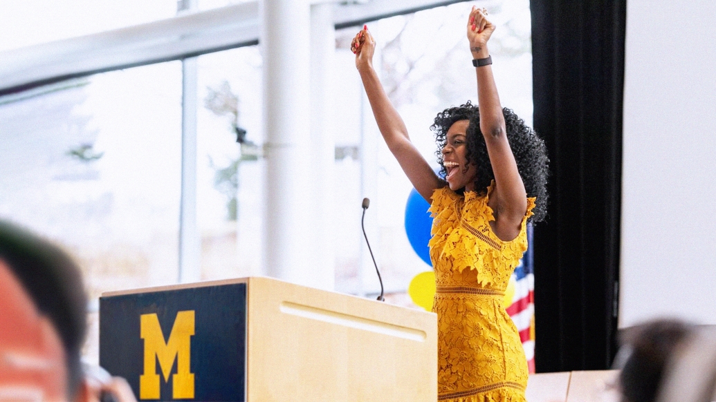 girl in yellow dress raising hands at podium