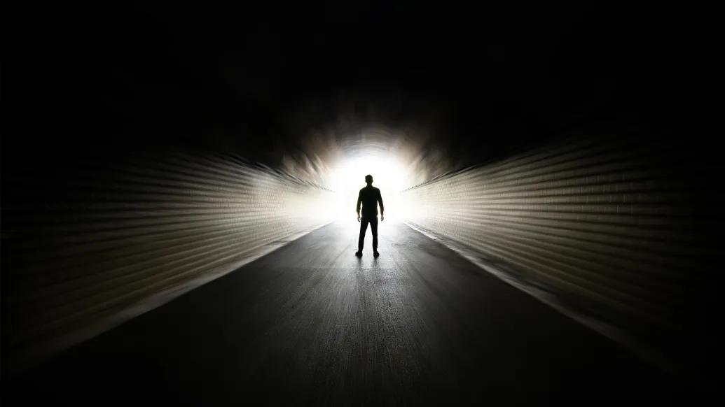black room with person visual far away walking towards glowing light