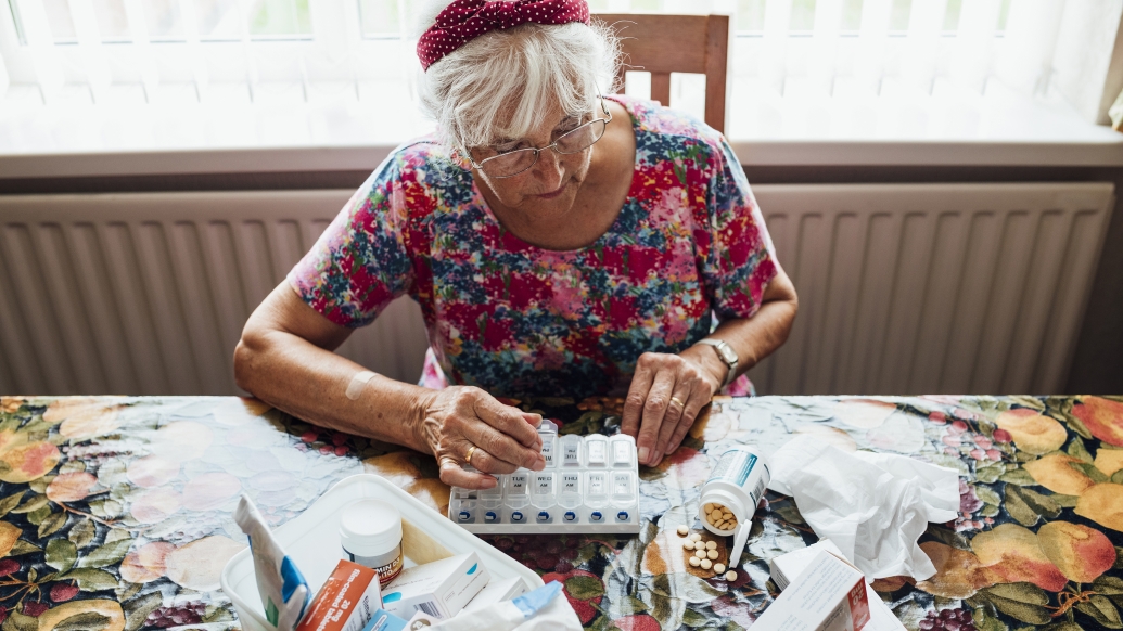 older woman at table with medicine pills in front of her