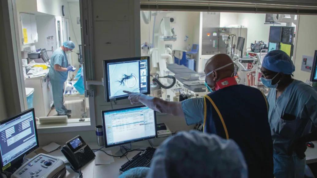 doctors in surgery case looking at screen blue scrubs