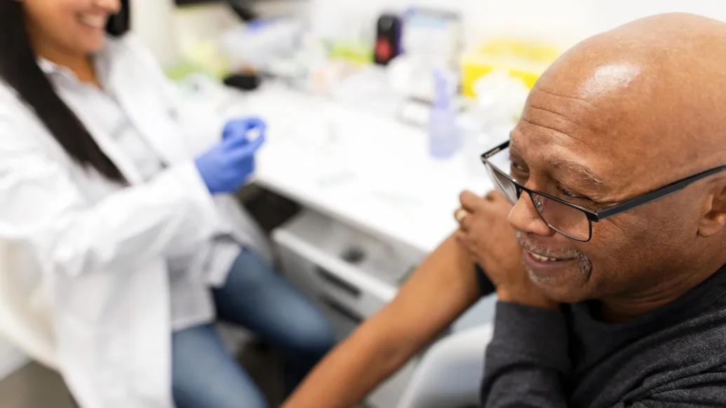 older gentleman getting vaccine arm rolled up