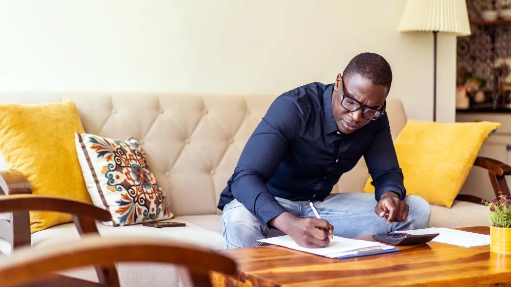 man at table writing down in living room