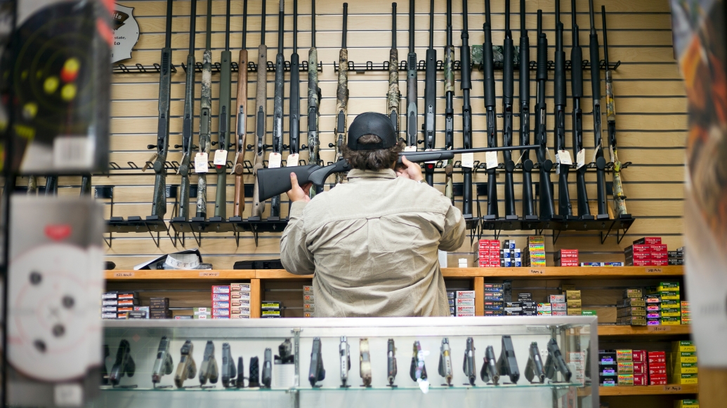 man looking at guns clerk store