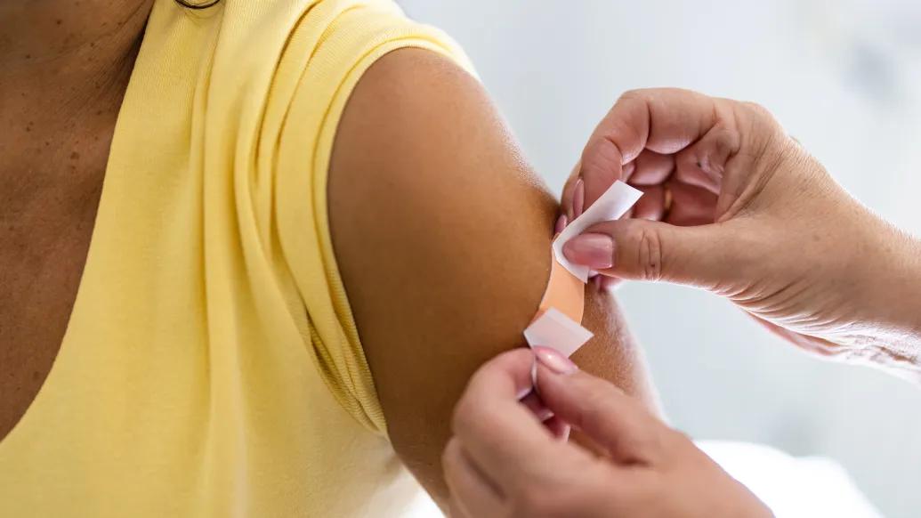 bandaid on arm after shot yellow shirt