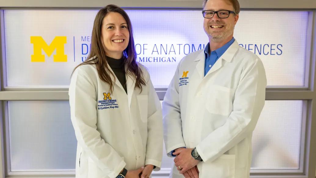 two scientists next to eachother smiling at camera white coats