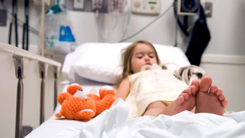 child in emergency room hospital bed with teddy bear 