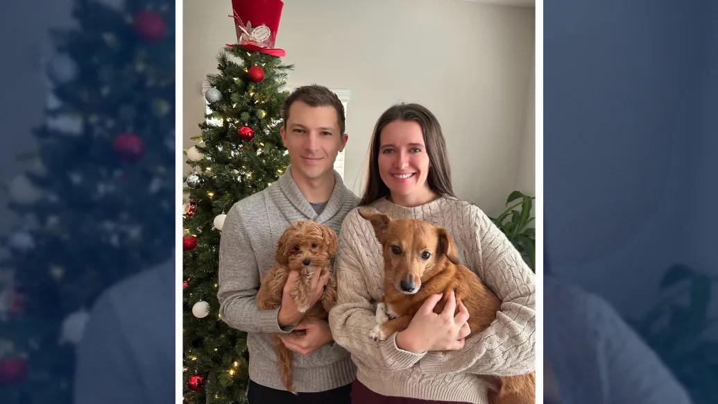 man woman holding brown small dogs christmas photo smiling neutral color sweaters grey biege 