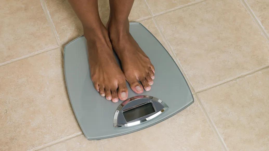 person's feet on scale on biege tile floor