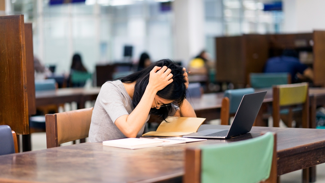 woman holding head down in library