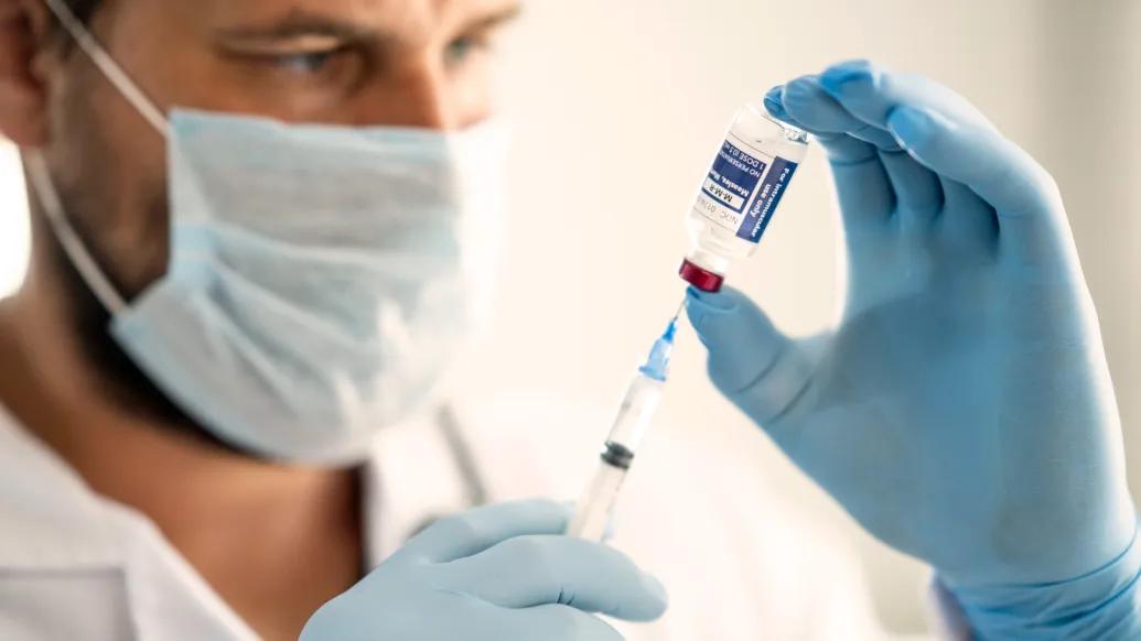 Health care provider loads syringe with measles vaccine