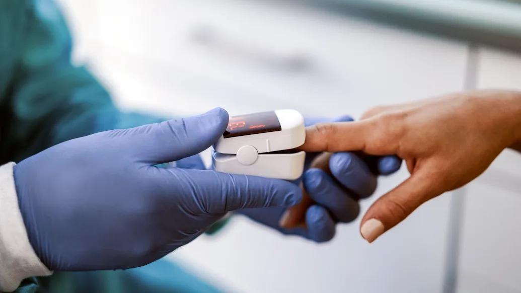 Provider takes a pulse oximetry reading from a patient's finger