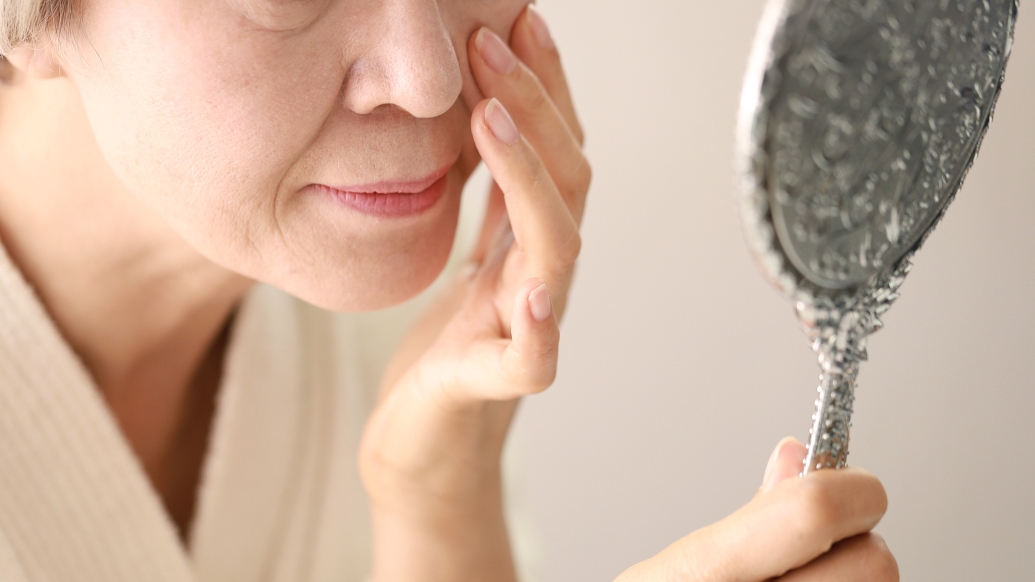 Older woman checks her face in the mirror