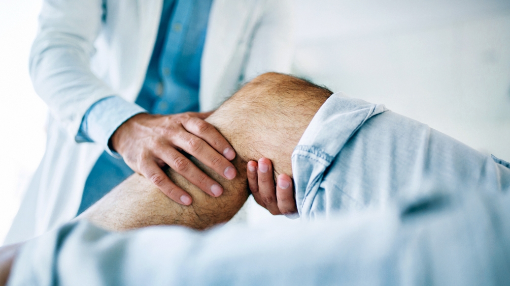 Closeup of knee with caregiver holding the joint and examining it.
