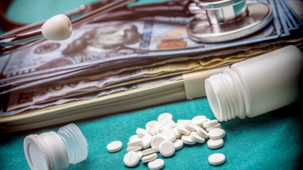 Spilled pills next to a stethoscope and pile of cash