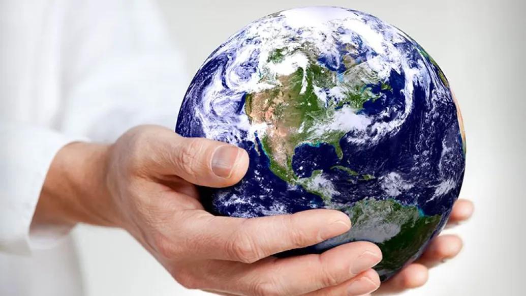 Hands holding a miniature version of the planet Earth. 