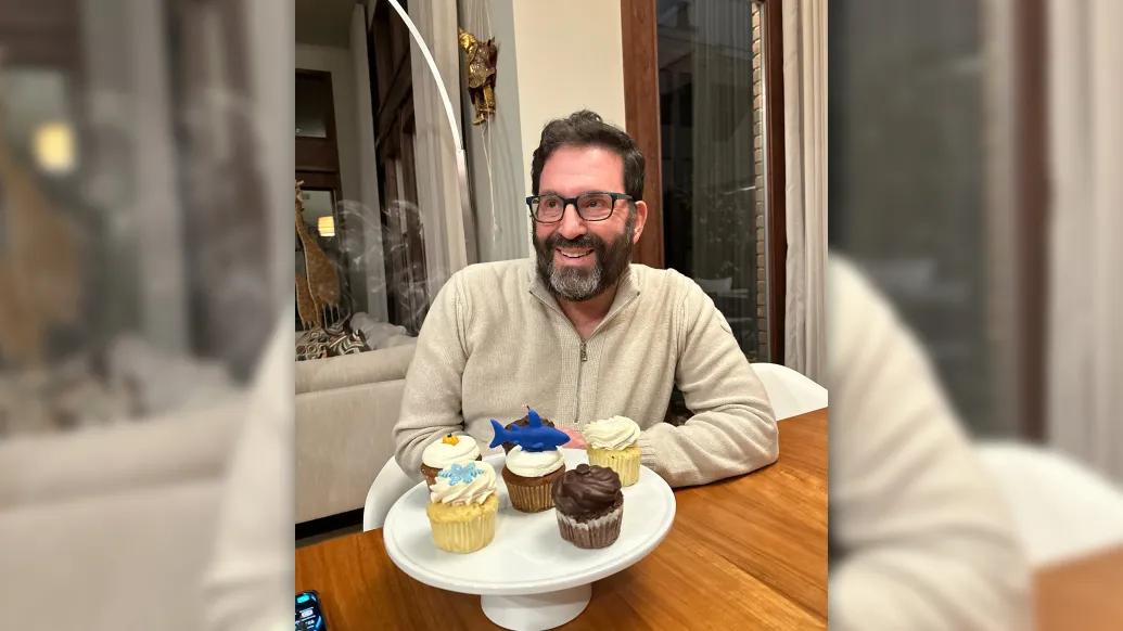 man smiling with cupcakes glasses