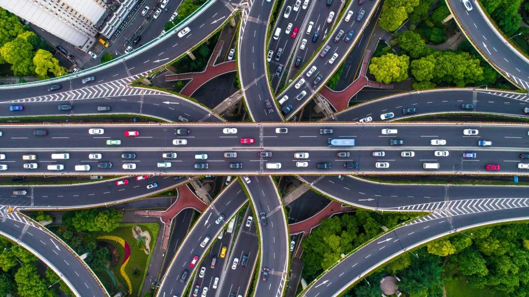 different cars from helicopter view on highways intersecting going all different ways seeing greenery and roads