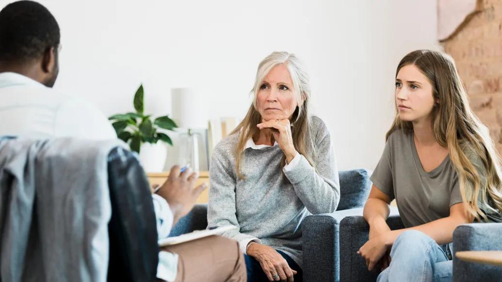 two women, one older one younger, looking concerned listening to a provider across from them with back to camera