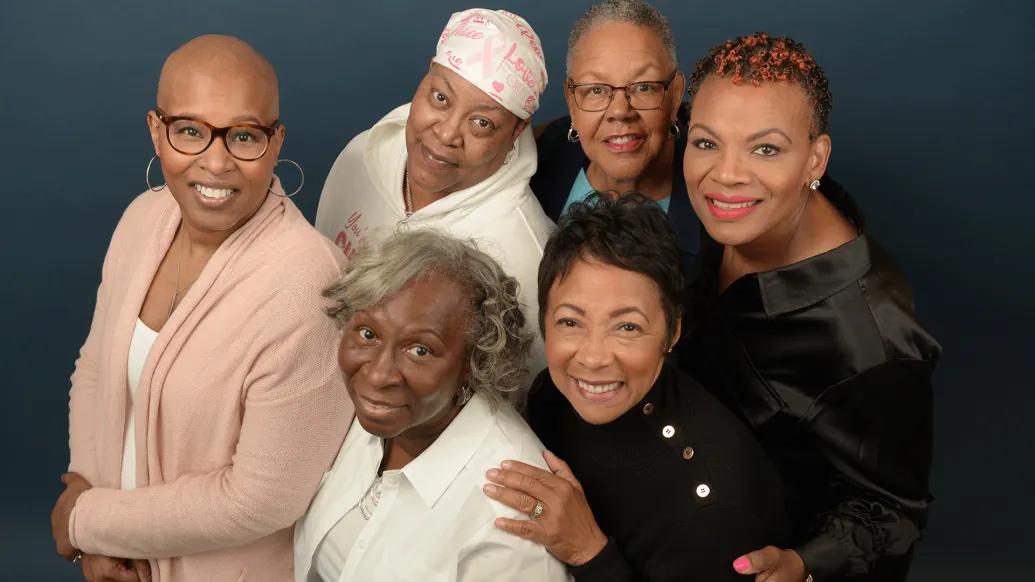 Group photo of six Black women who are breast cancer survivors. They are all looking up at the camera and smiling.