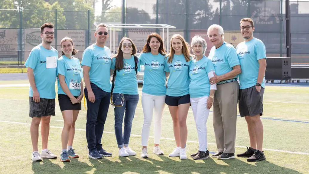 Sheeren Family wearing blue Run, Walk N Roll 5K t-shirts standing on football field.