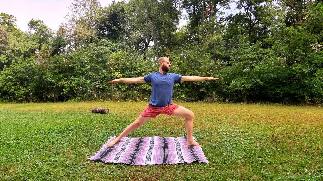 man practicing yoga outside over blanket