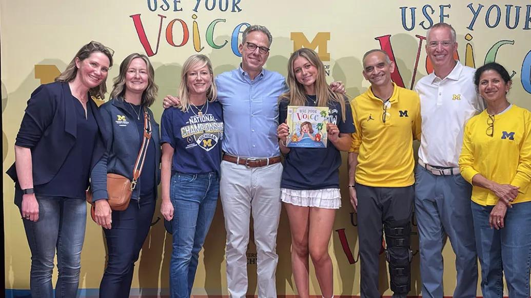 Smiling photo of eight people standing in front of a backdrop that says, "Use Your Voice".