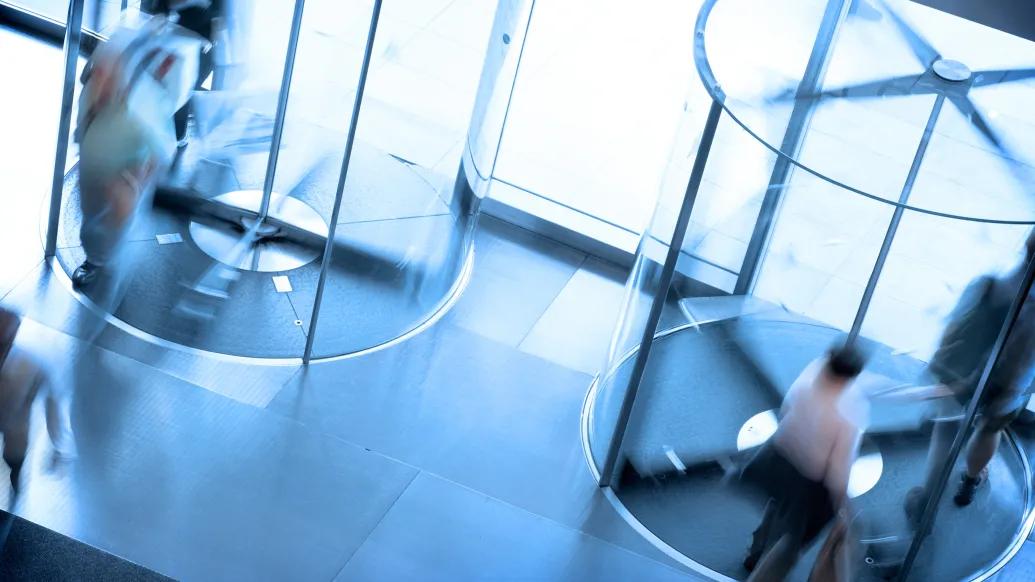 blurred front door exit with people walking through in blue see through doors