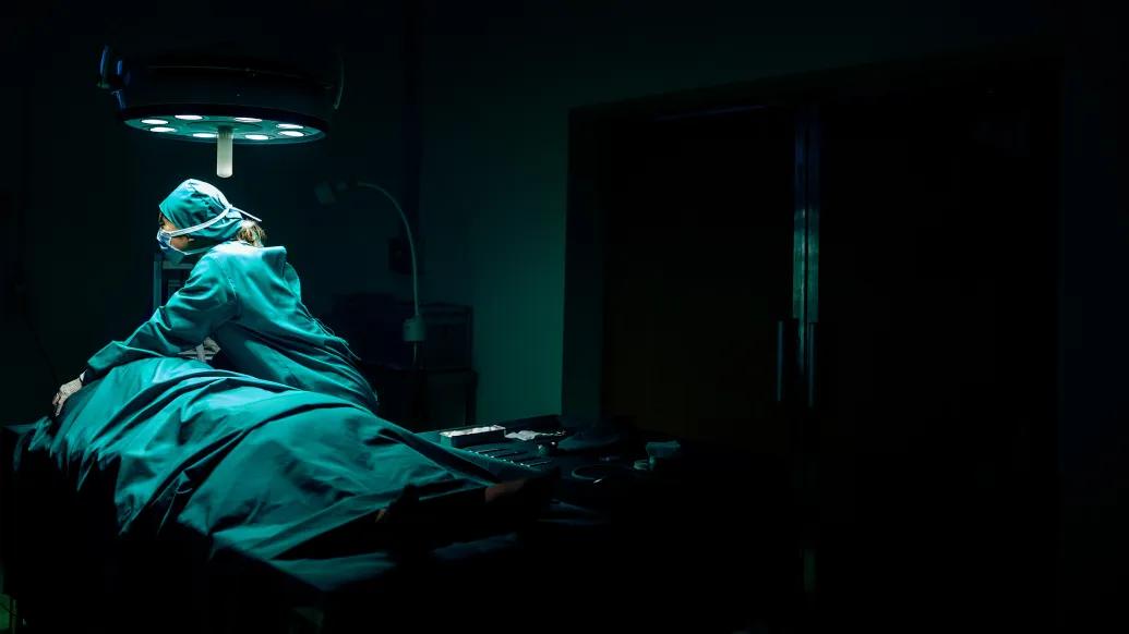 surgeon dark room over surgery patient on hospital table