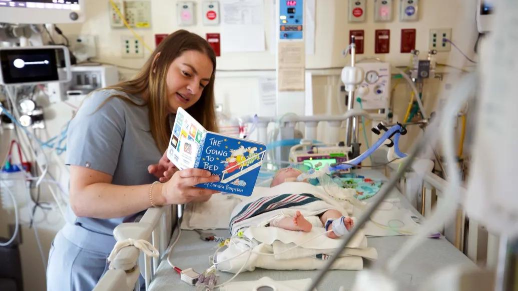 A Michigan Medicine employee reads to a baby in the Brandon Neonatal Intensive Care Unit.