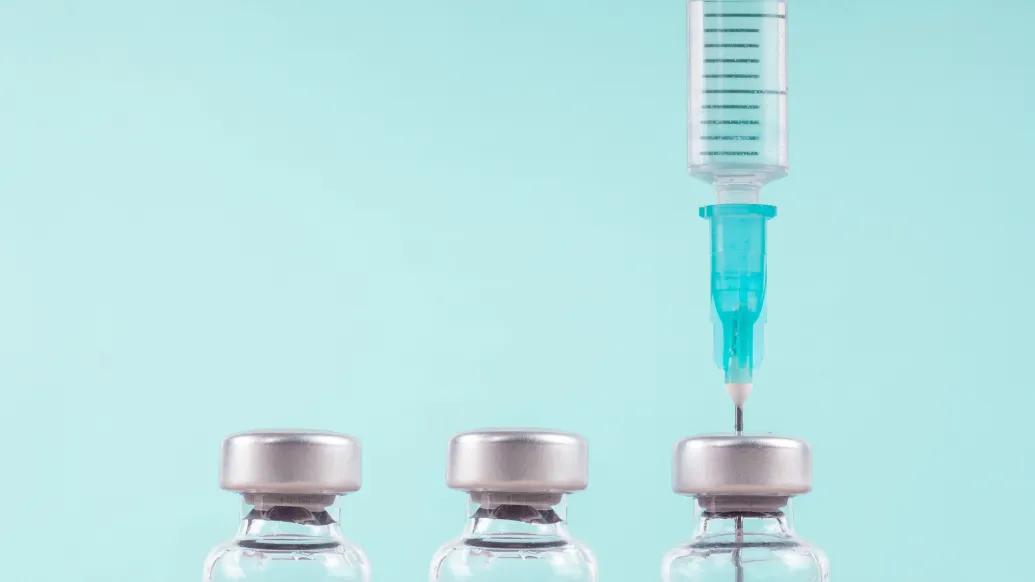 syringes three in a row with one with a shot going into it on a light teal background