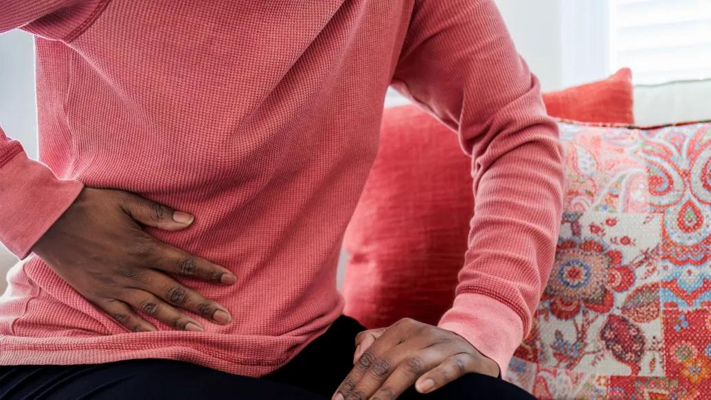man in pink shirt close up with hand on stomach