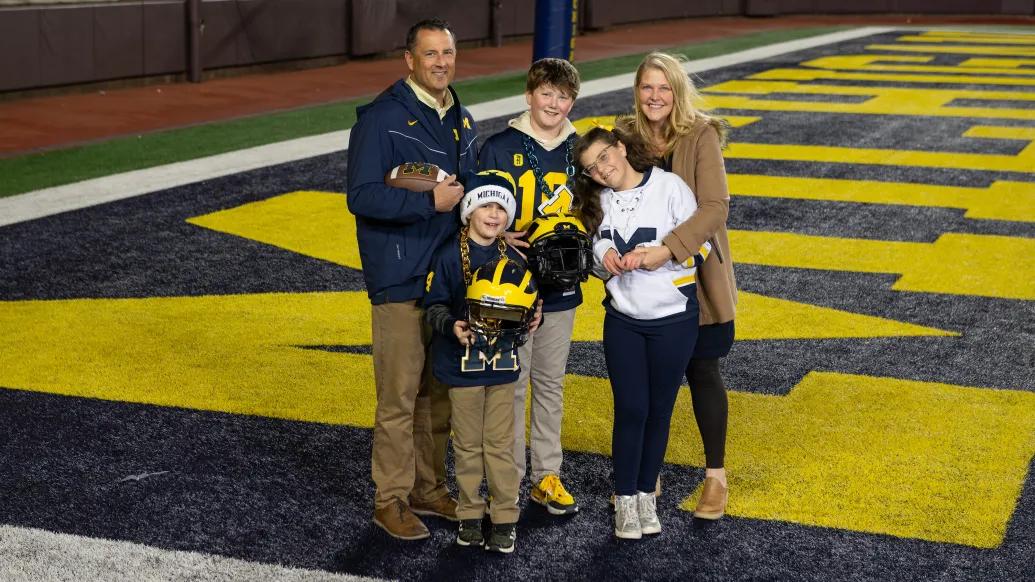 family photo on michigan football field with michigan colors