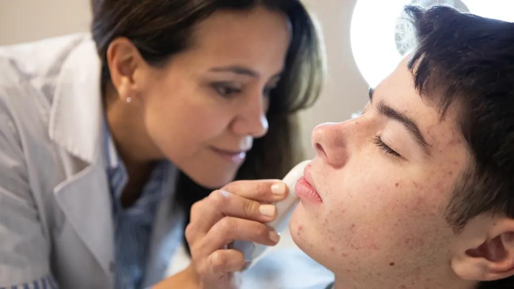 doctor looking close up at patients skin with microscope-like tool