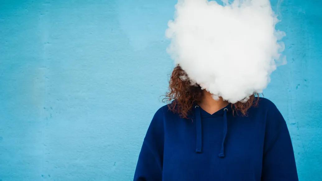 smoke over face of person with blue sweatshirt blue background