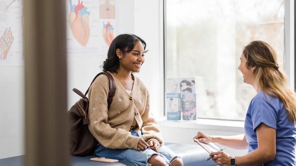 a patient with a medical professional in scrubs in an exam room talking
