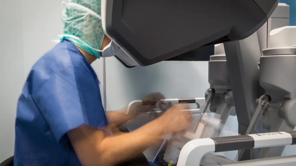 doctor looking into robotic set up in scrubs and scrub hat