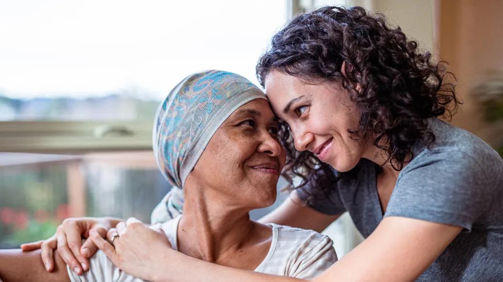 two women hugging with cap over hair