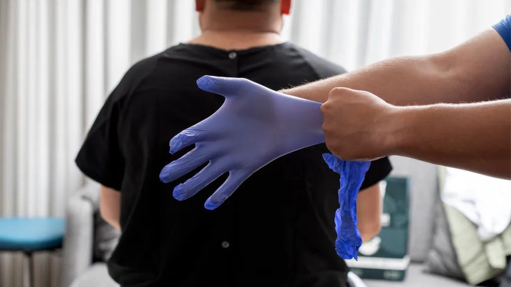 medical glove purple behind patients back being put on