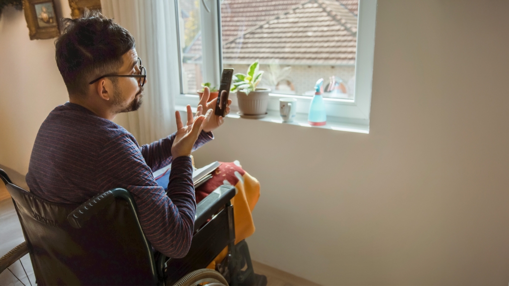 man in wheelchair at home with phone talking on facetime