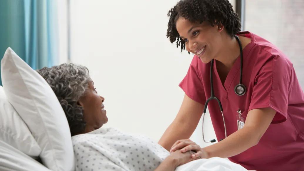 nurse in maroon at patient bedside