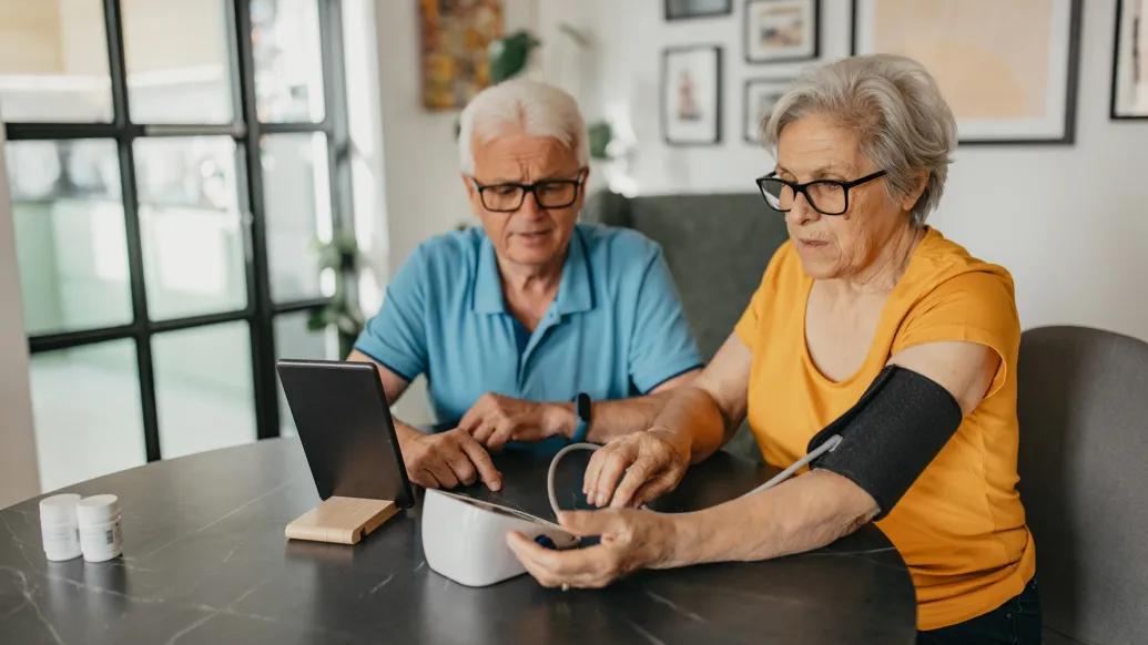 two older people taking blood pressure over breakfast